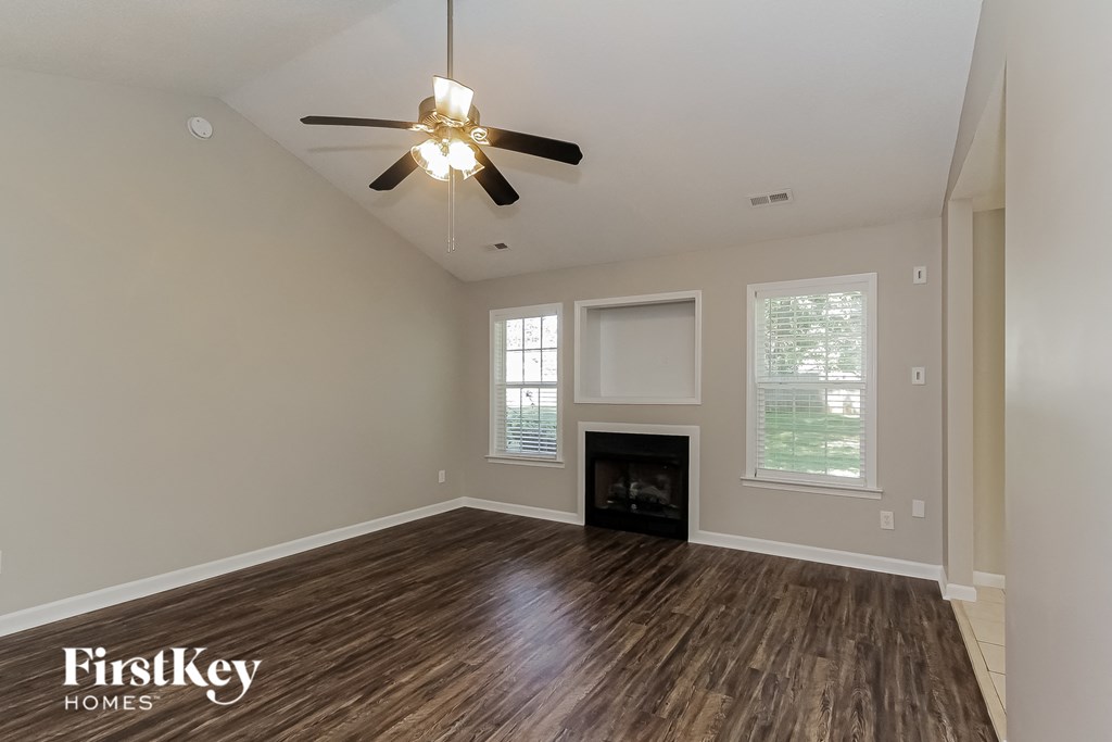 the living room of a home with a fireplace and a ceiling fan