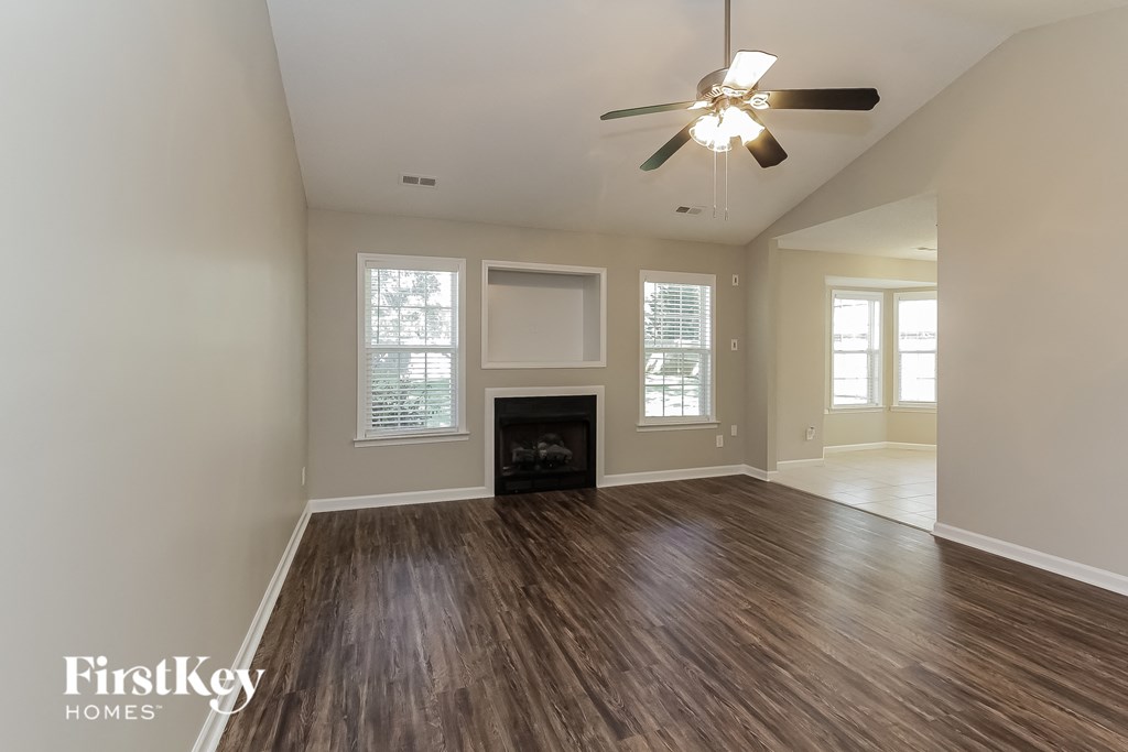 an empty living room with a ceiling fan and a fireplace