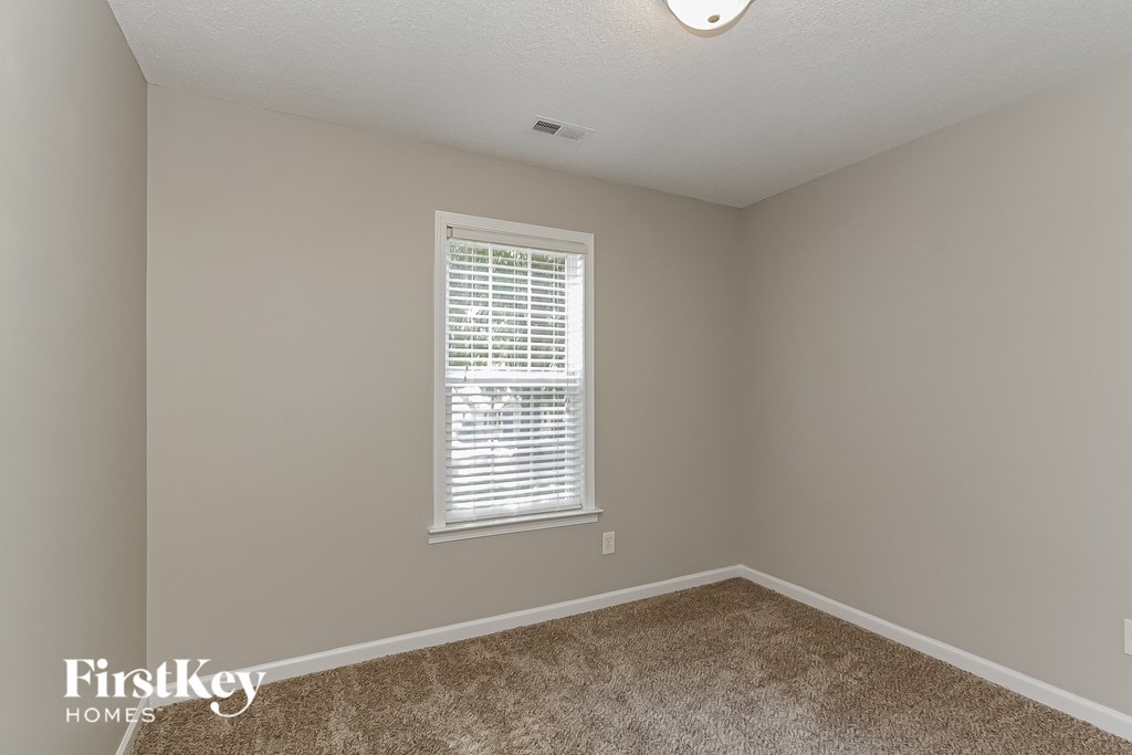 a bedroom with a window and a carpeted floor