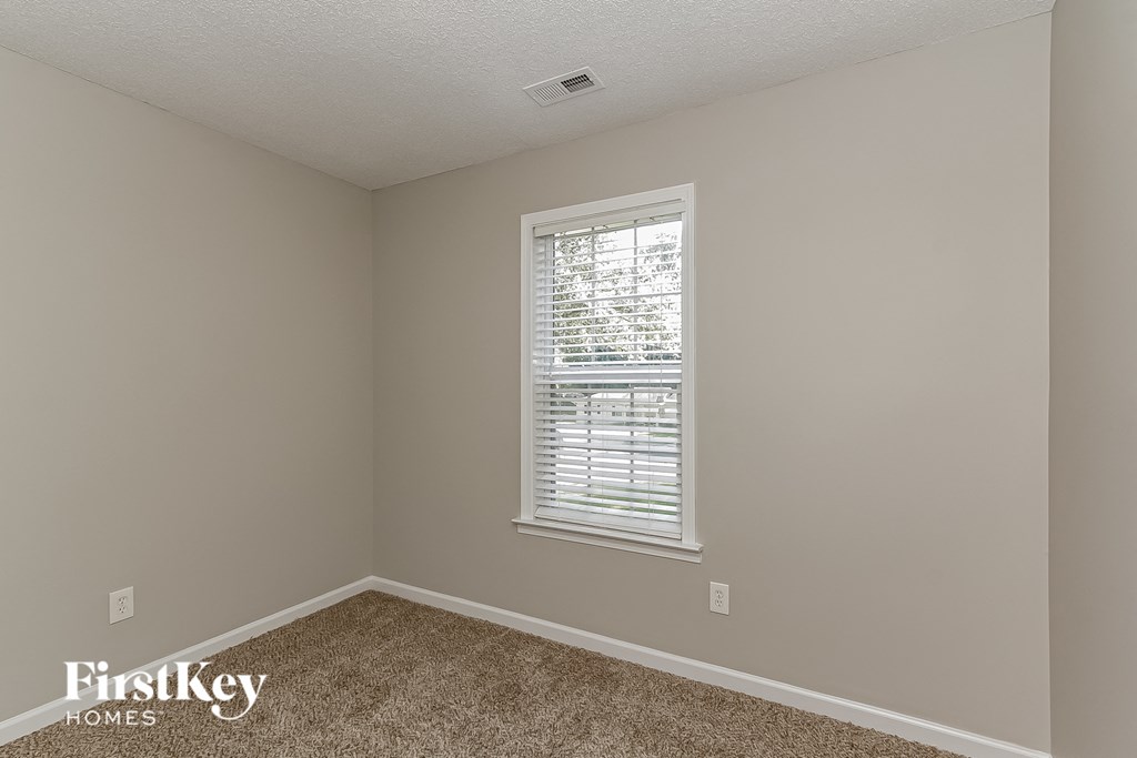 a bedroom with a window and a carpeted floor