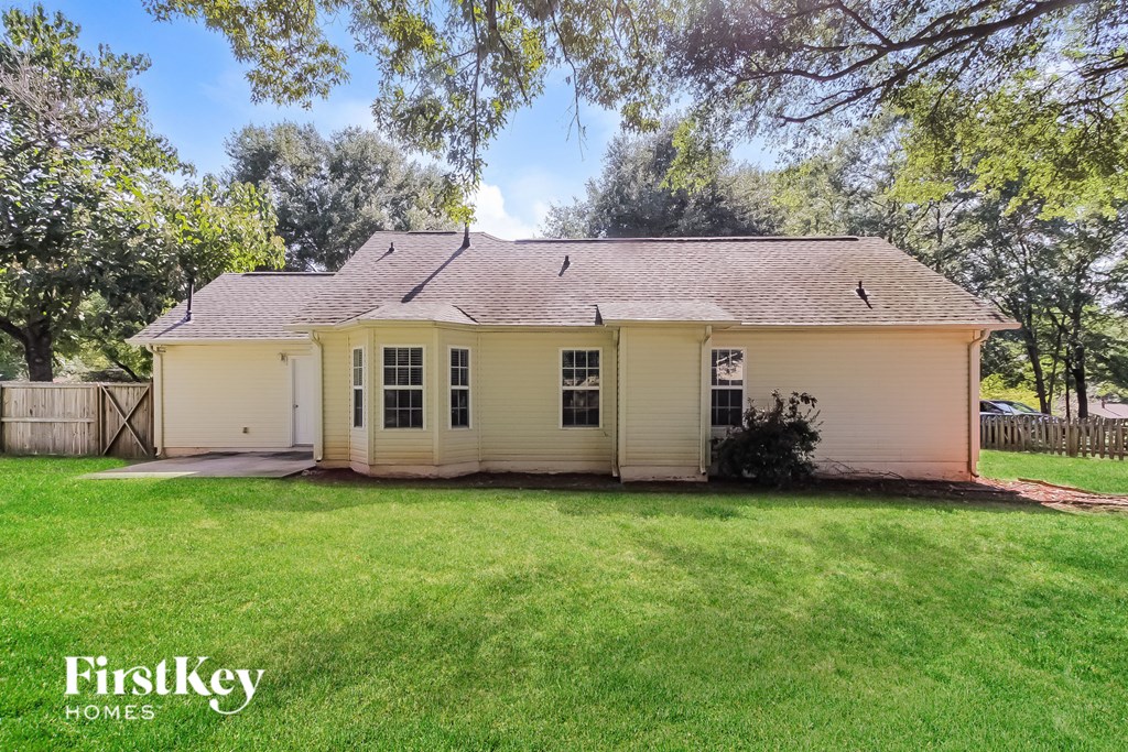 a small yellow house with a grassy yard and trees