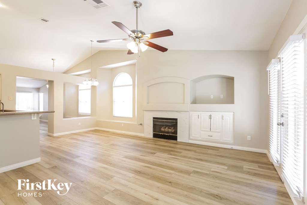 A spacious living room with a fireplace and a ceiling fan.
