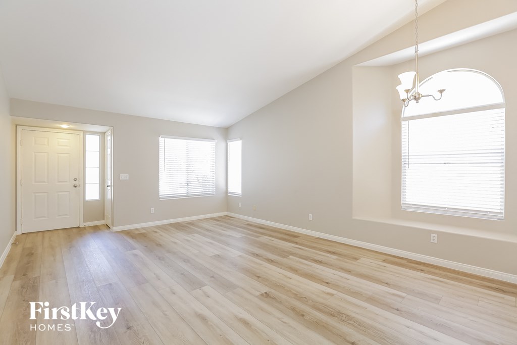 A spacious room with wooden flooring and a large arched window.