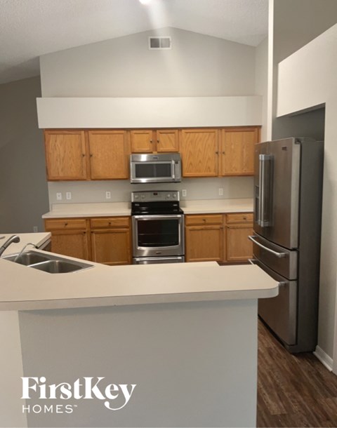 A kitchen with wooden cabinets and a stainless steel refrigerator.