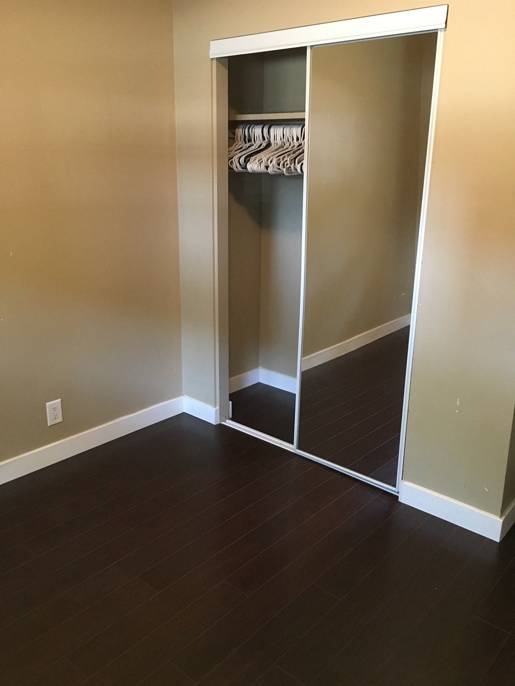 an open closet in a living room with wood flooring