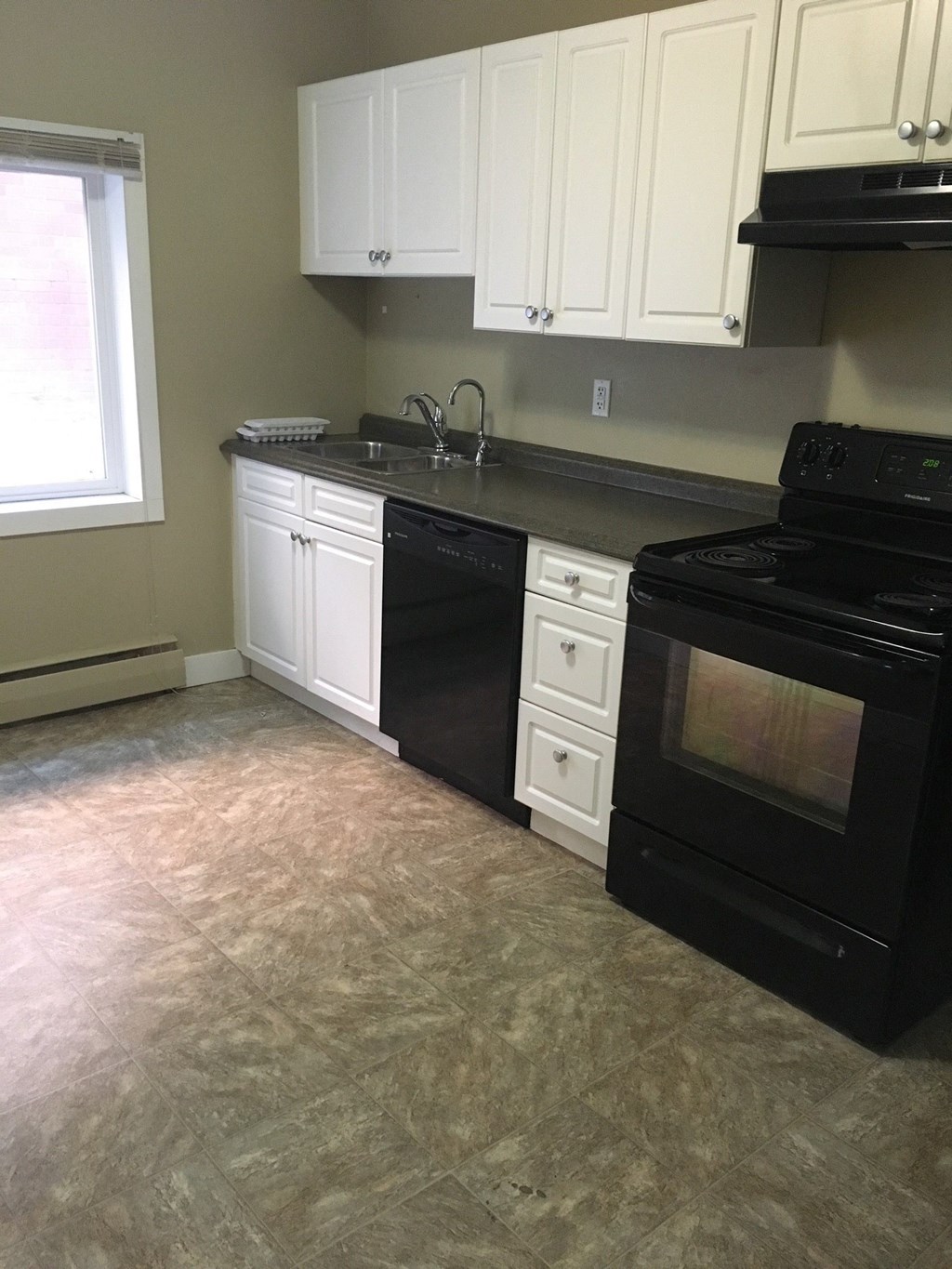 an empty kitchen with black appliances and white cabinets