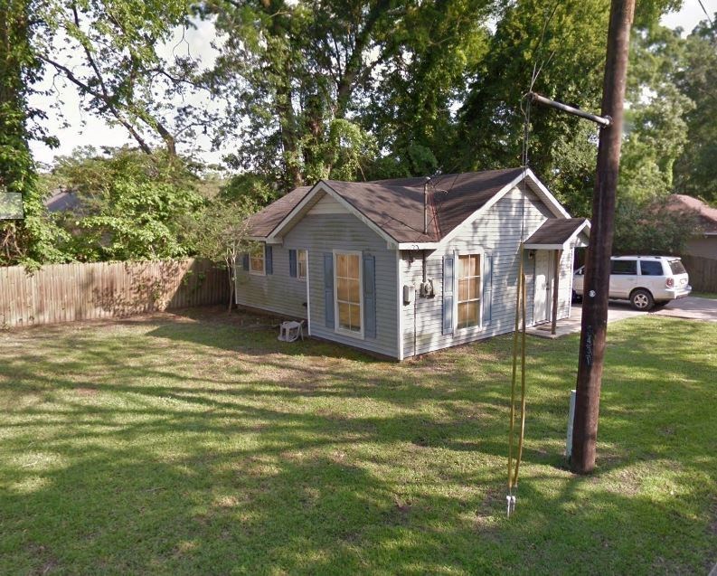 a small house in a backyard with a yard and a pole