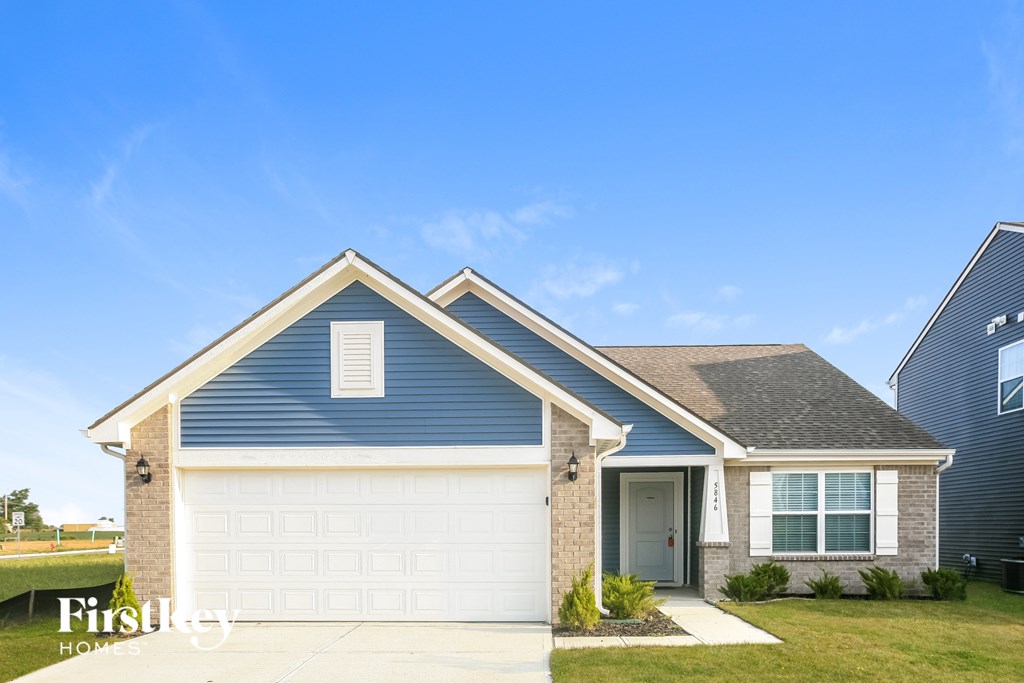 A blue house with a white garage door and a brown brick wall.