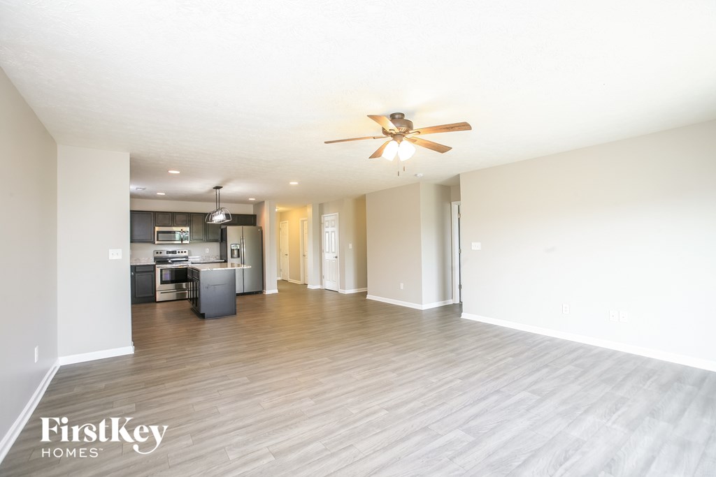 A spacious room with a ceiling fan and wooden flooring.