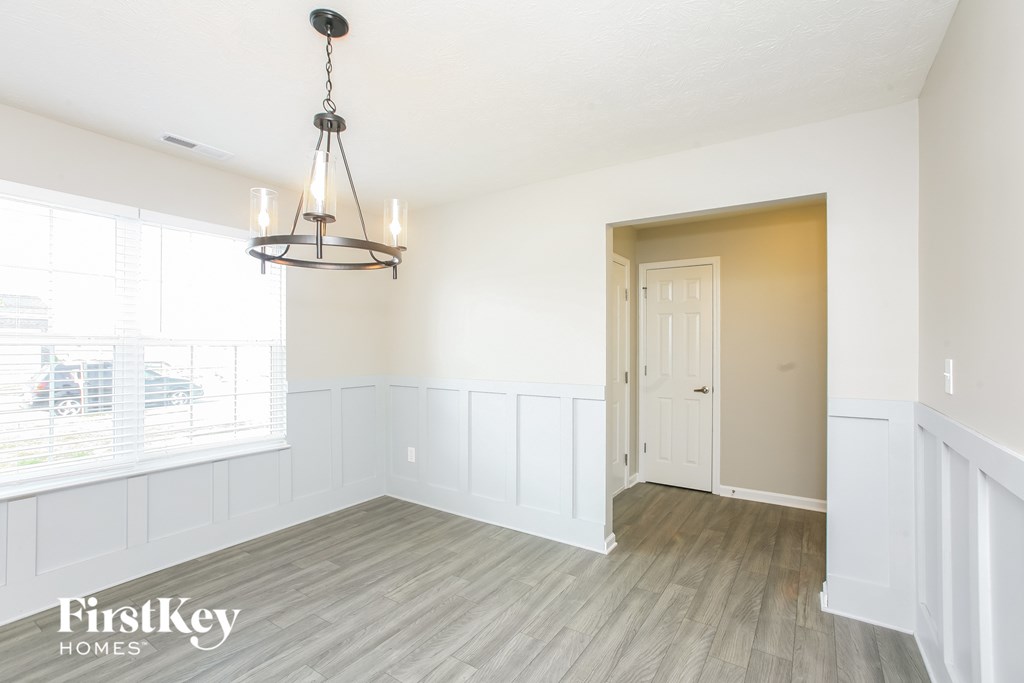A room with a wooden floor and a chandelier hanging from the ceiling.