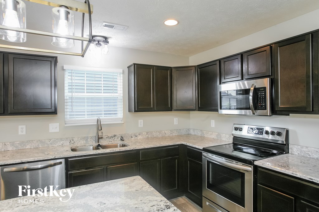A kitchen with dark brown cabinets and a granite countertop.