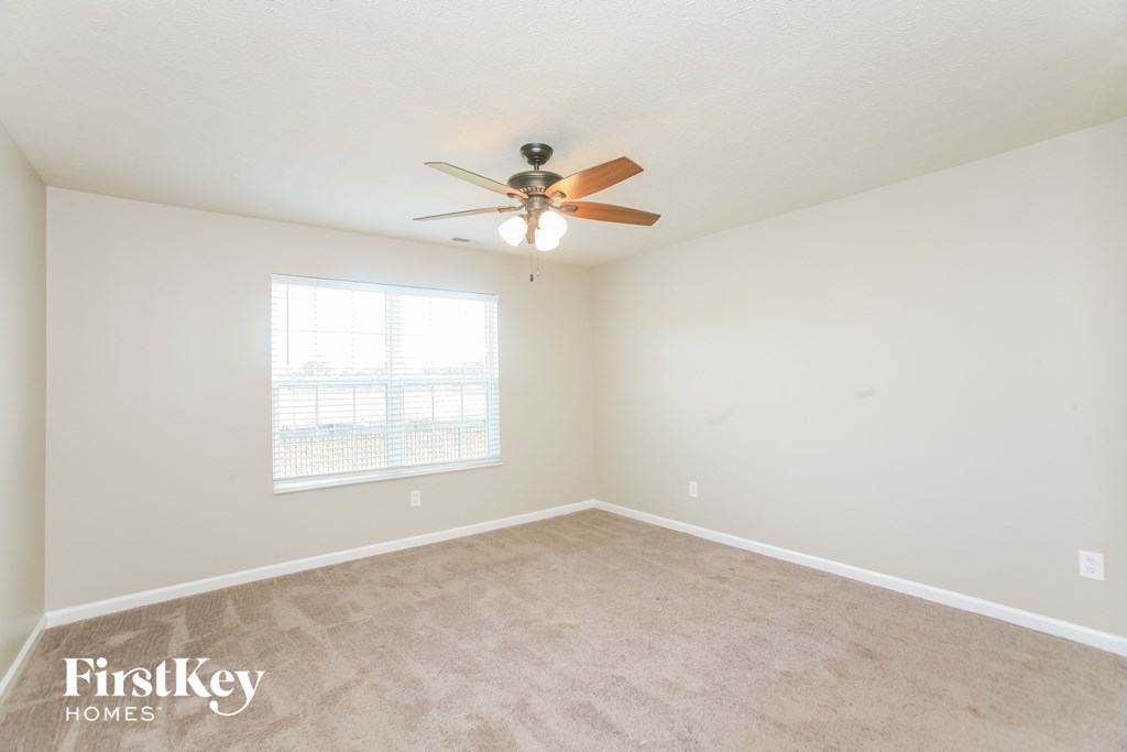 A spacious room with a ceiling fan and a window.