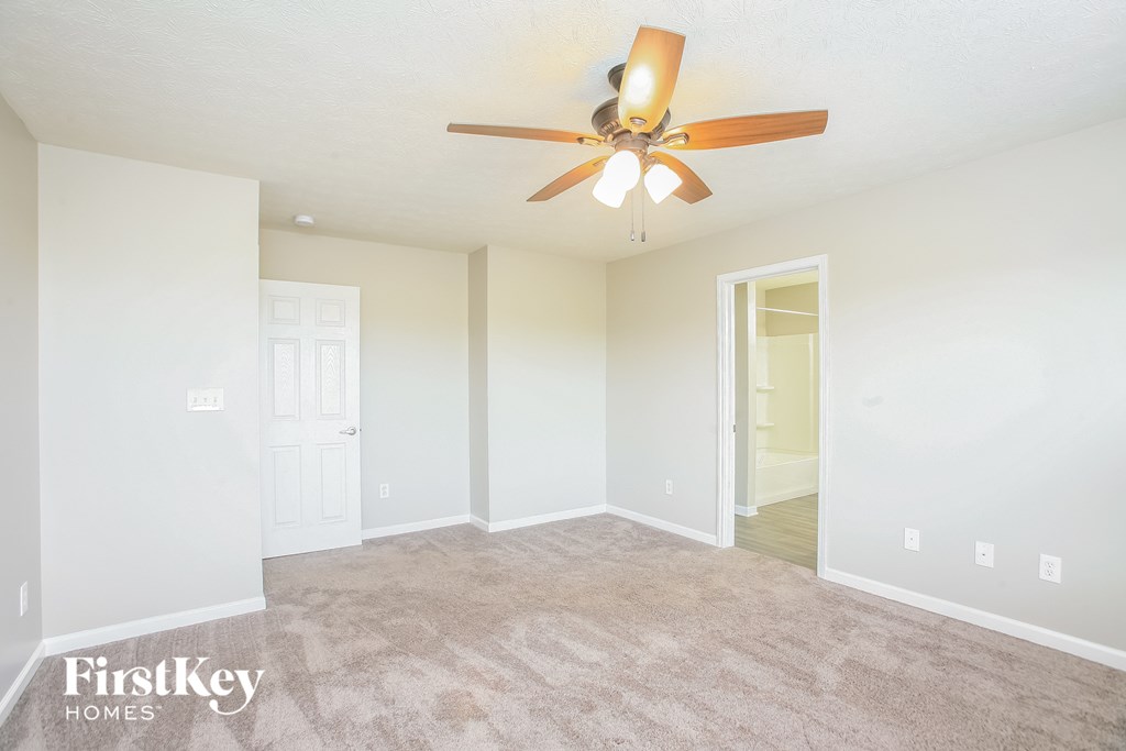 A spacious room with a ceiling fan and carpeted floor.