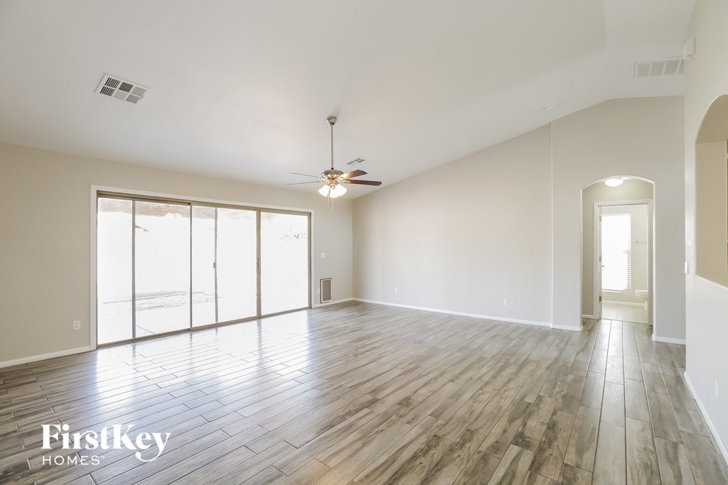 an empty living room with wood floors and a ceiling fan