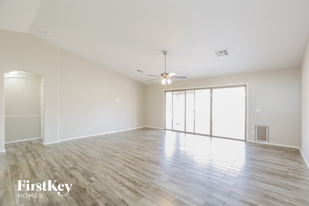 a spacious living room with hardwood floors and a ceiling fan