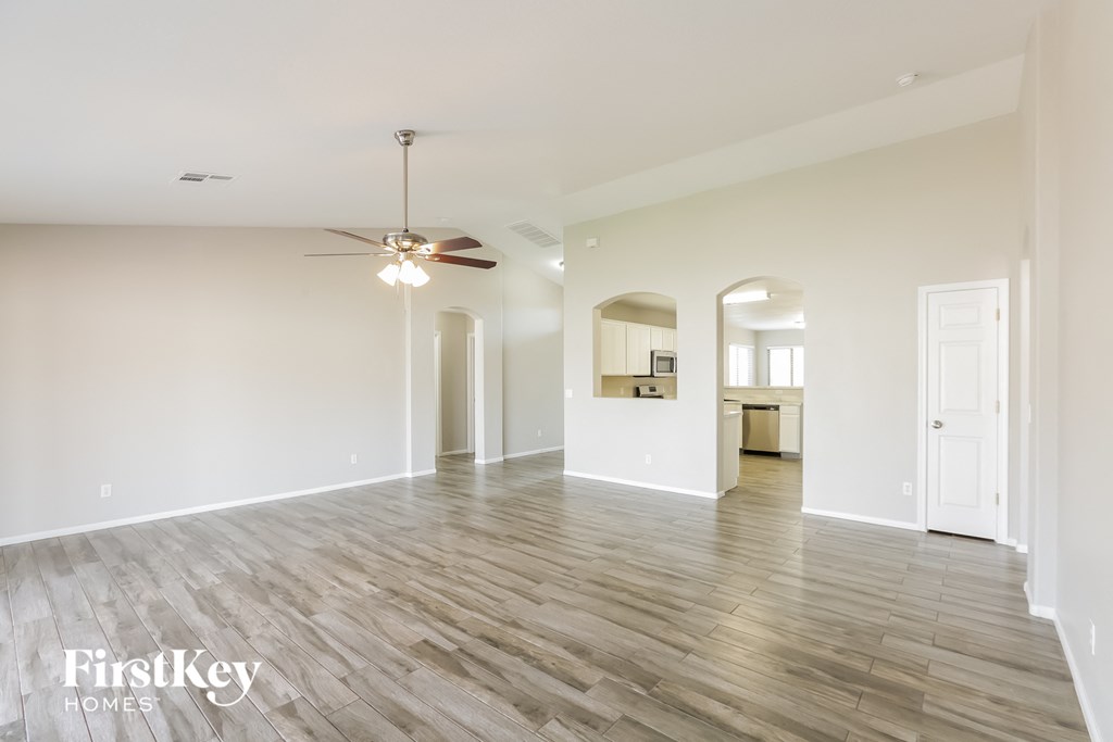 a living room with white walls and a ceiling fan