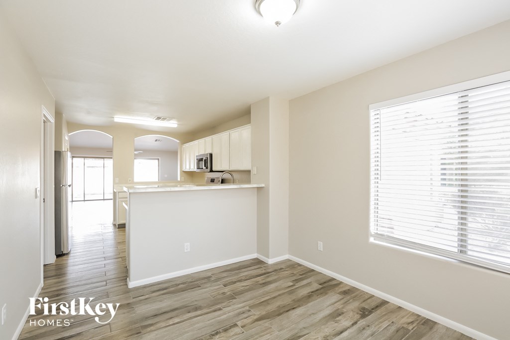 the living room and kitchen of an apartment with wood flooring and a large window