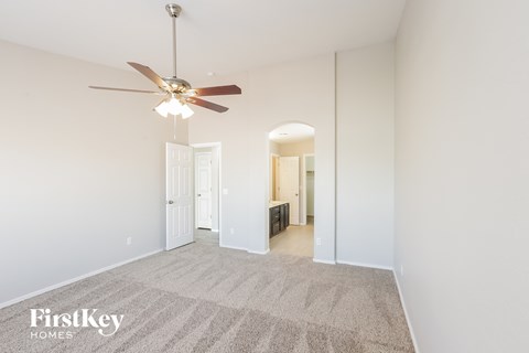 a spacious living room with carpet and a ceiling fan