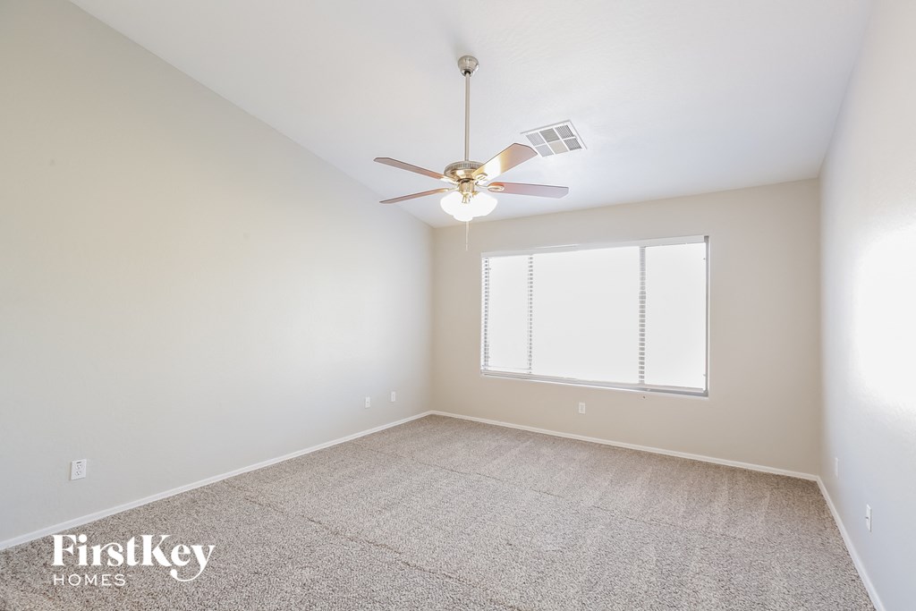 an empty room with a ceiling fan and a window
