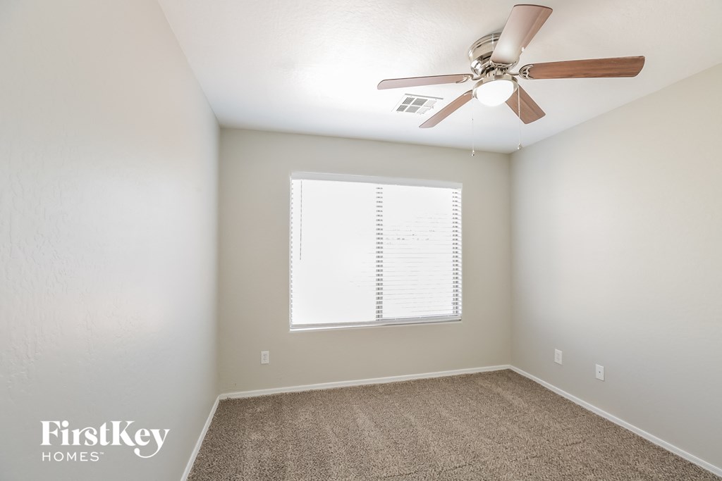 an empty room with a ceiling fan and a window