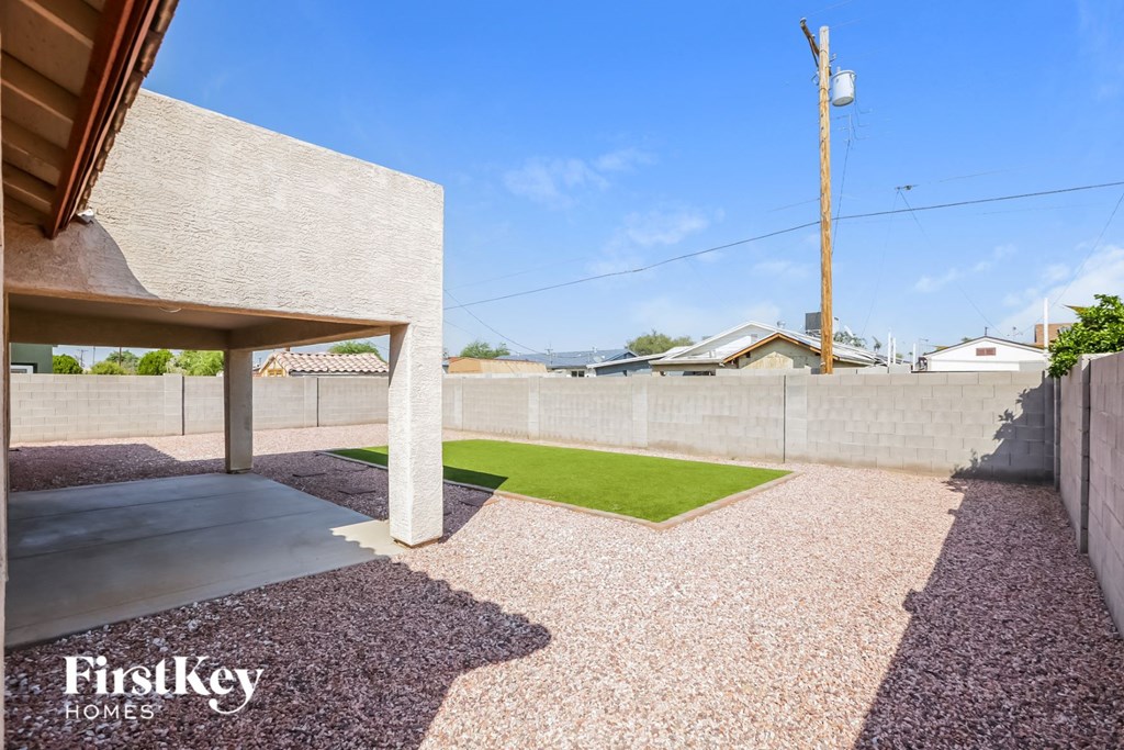 a backyard with a grass lawn and a concrete wall