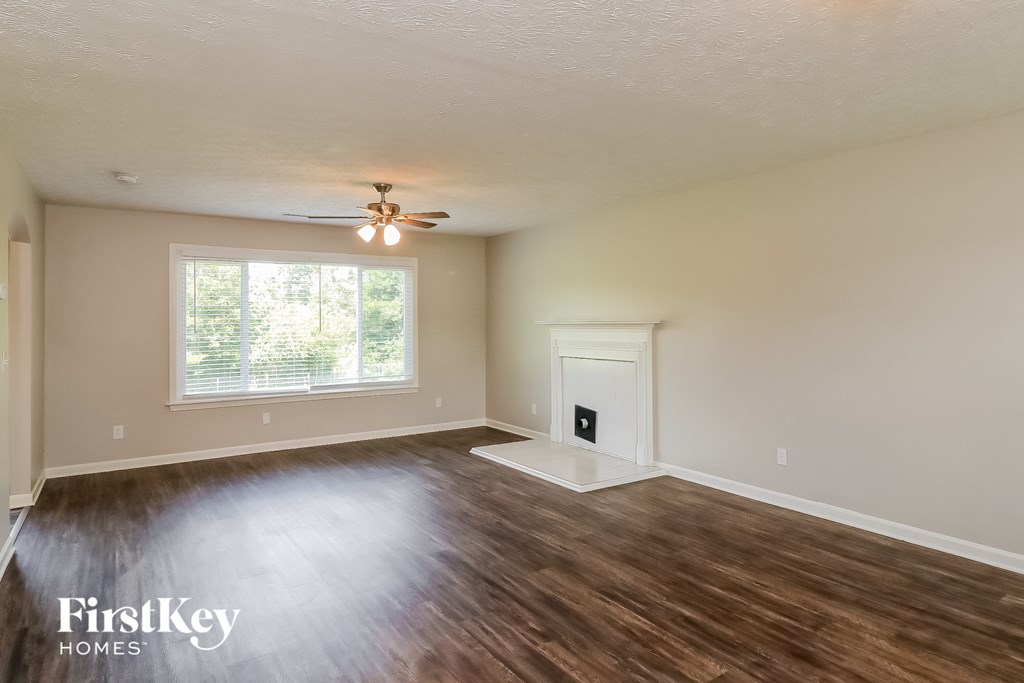 the living room of an empty house with wood flooring and a ceiling fan