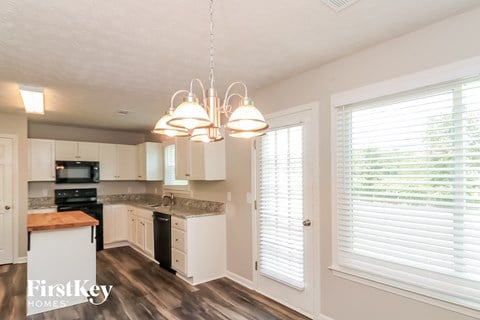 a kitchen with white cabinets and a large window