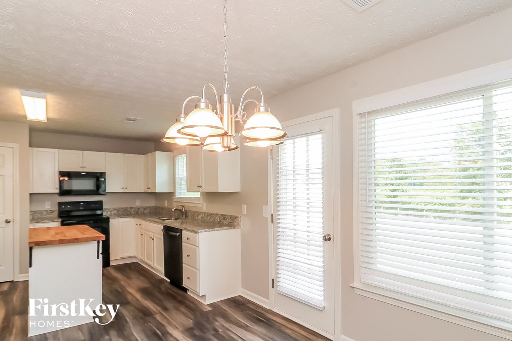 a kitchen with white cabinets and a large window