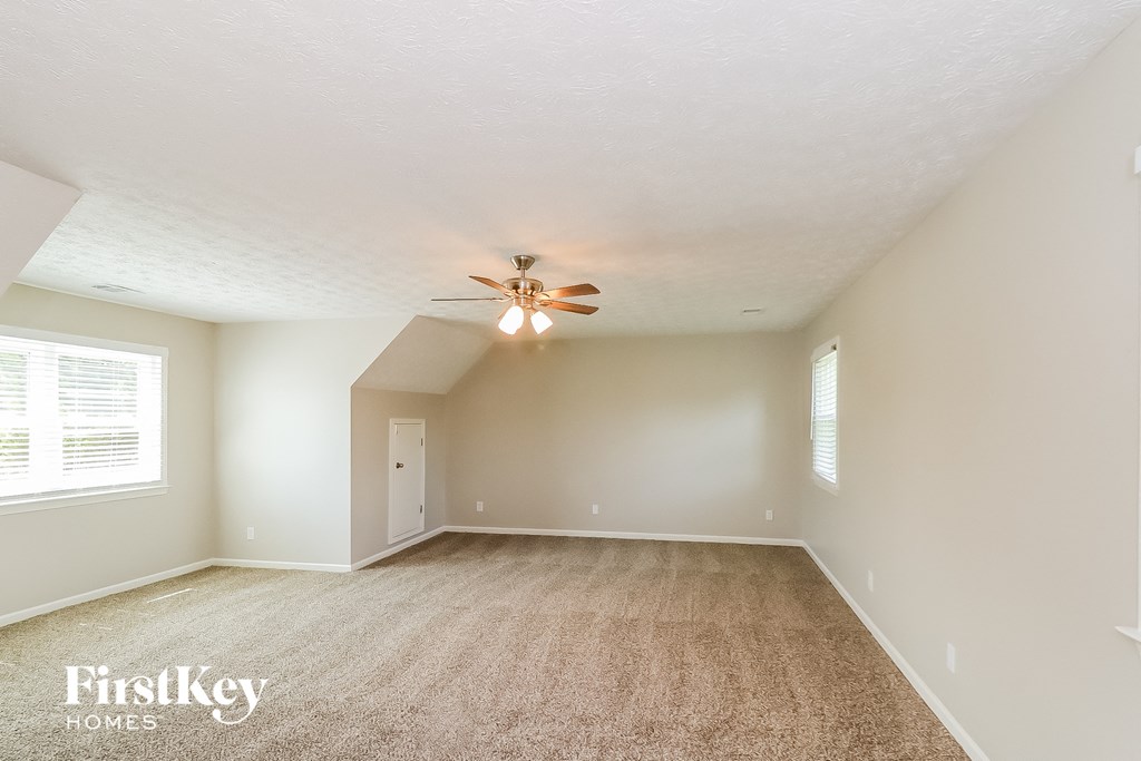 a spacious living room with carpet and a ceiling fan