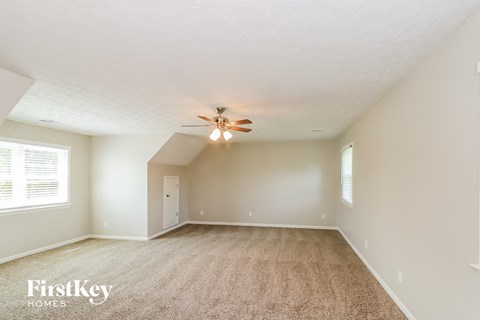 a spacious living room with carpet and a ceiling fan