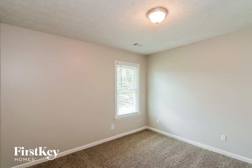a bedroom with white walls and white carpet and a window