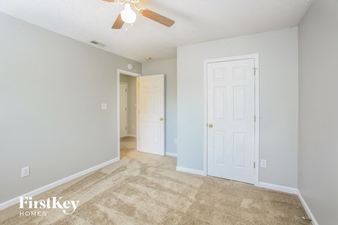a living room with a white door and a ceiling fan