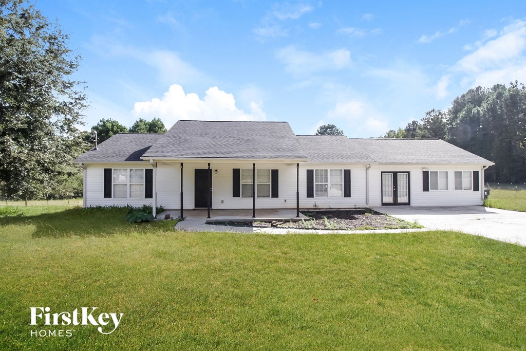 A white house with a black roof and a sign that says "FirstKey" in front of it.