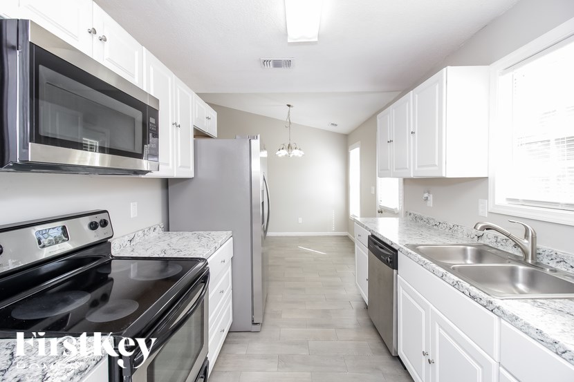 A kitchen with white cabinets and a black stove top oven.