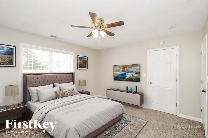 A bedroom with a large bed and a ceiling fan.