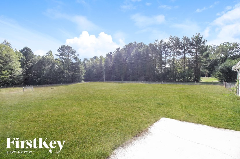 A grassy field with trees in the background and a FirstKey Homes logo.