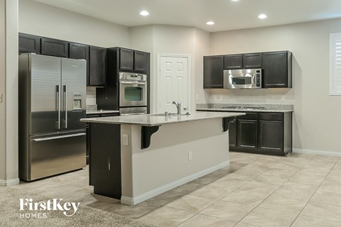 A kitchen with black cabinets and a stainless steel refrigerator.
