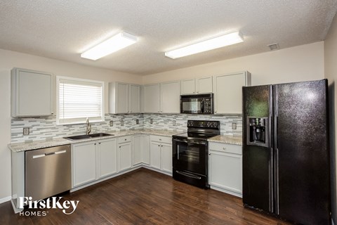 a kitchen with white cabinets and a black refrigerator