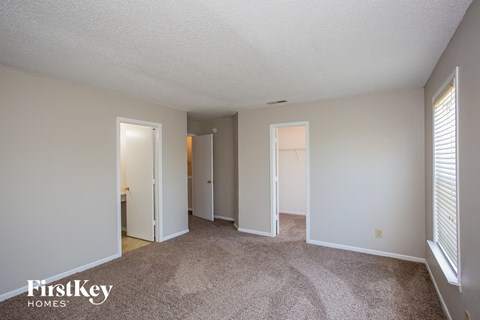 a spacious living room with white walls and carpet