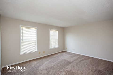 a bedroom with carpet and two windows