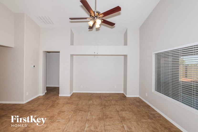 a empty living room with a ceiling fan and a window