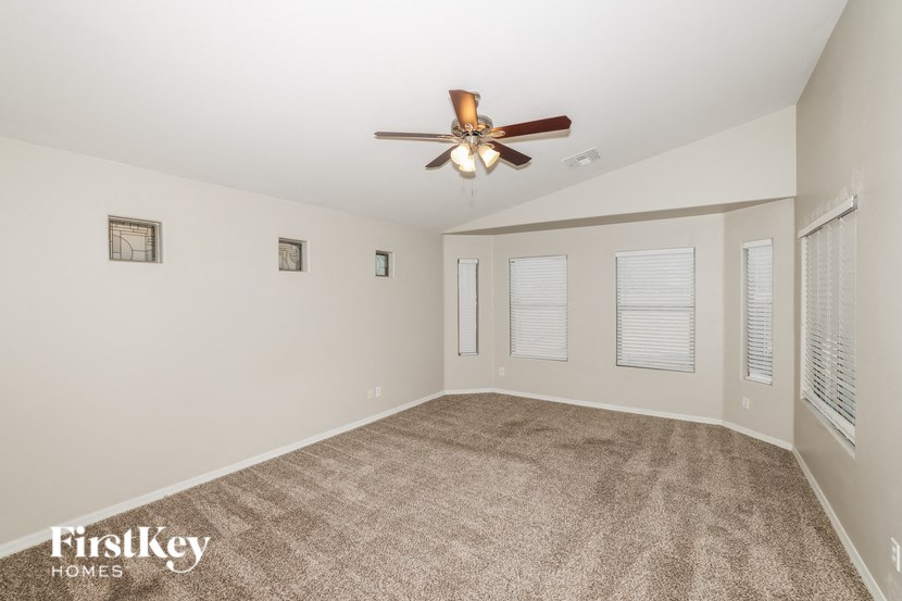 an empty living room with a ceiling fan and a carpet