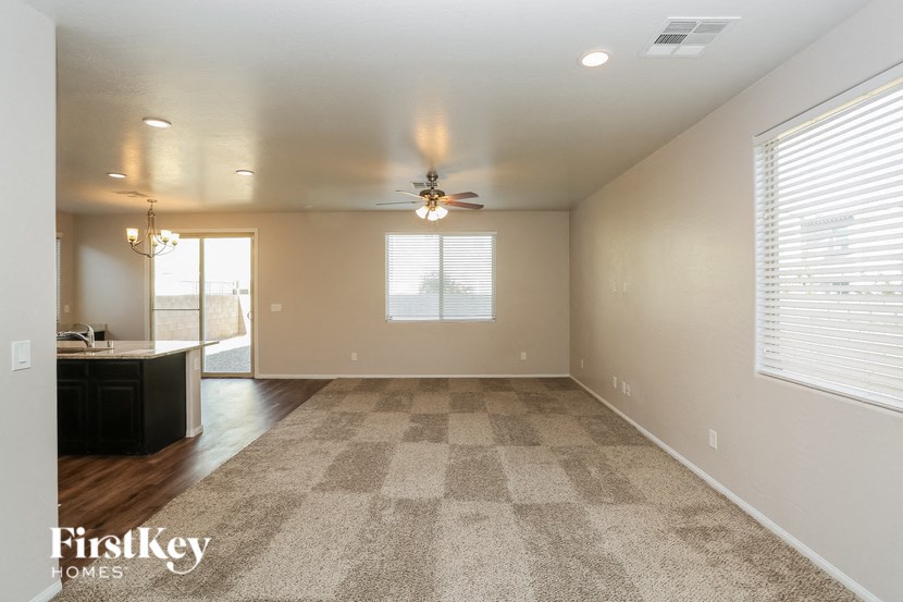 an empty living room with a ceiling fan and a window