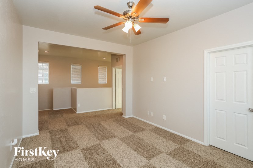 a living room with carpet and a ceiling fan
