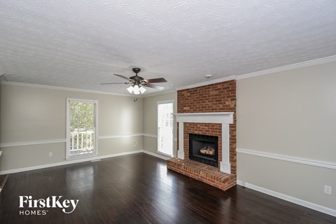 a living room with a brick fireplace and a ceiling fan