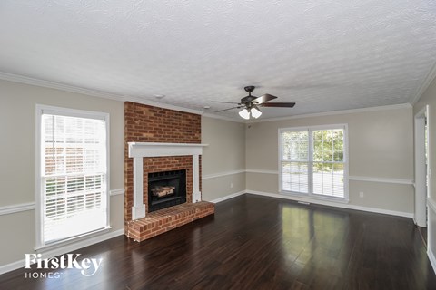 a living room with a brick fireplace and a ceiling fan