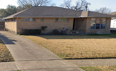 a brick house with a sidewalk in front of it