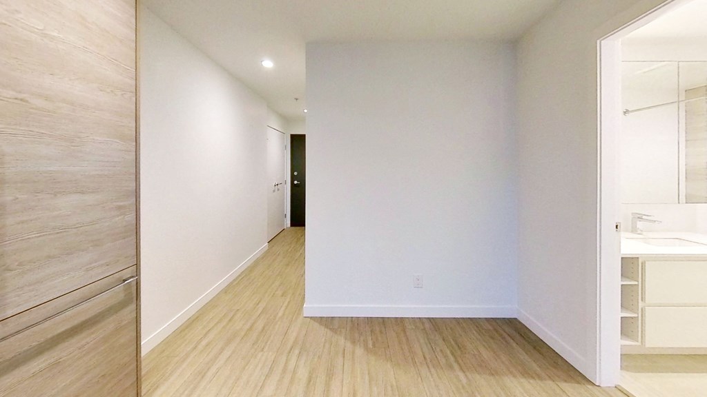 an empty hallway with white walls and wood floors
