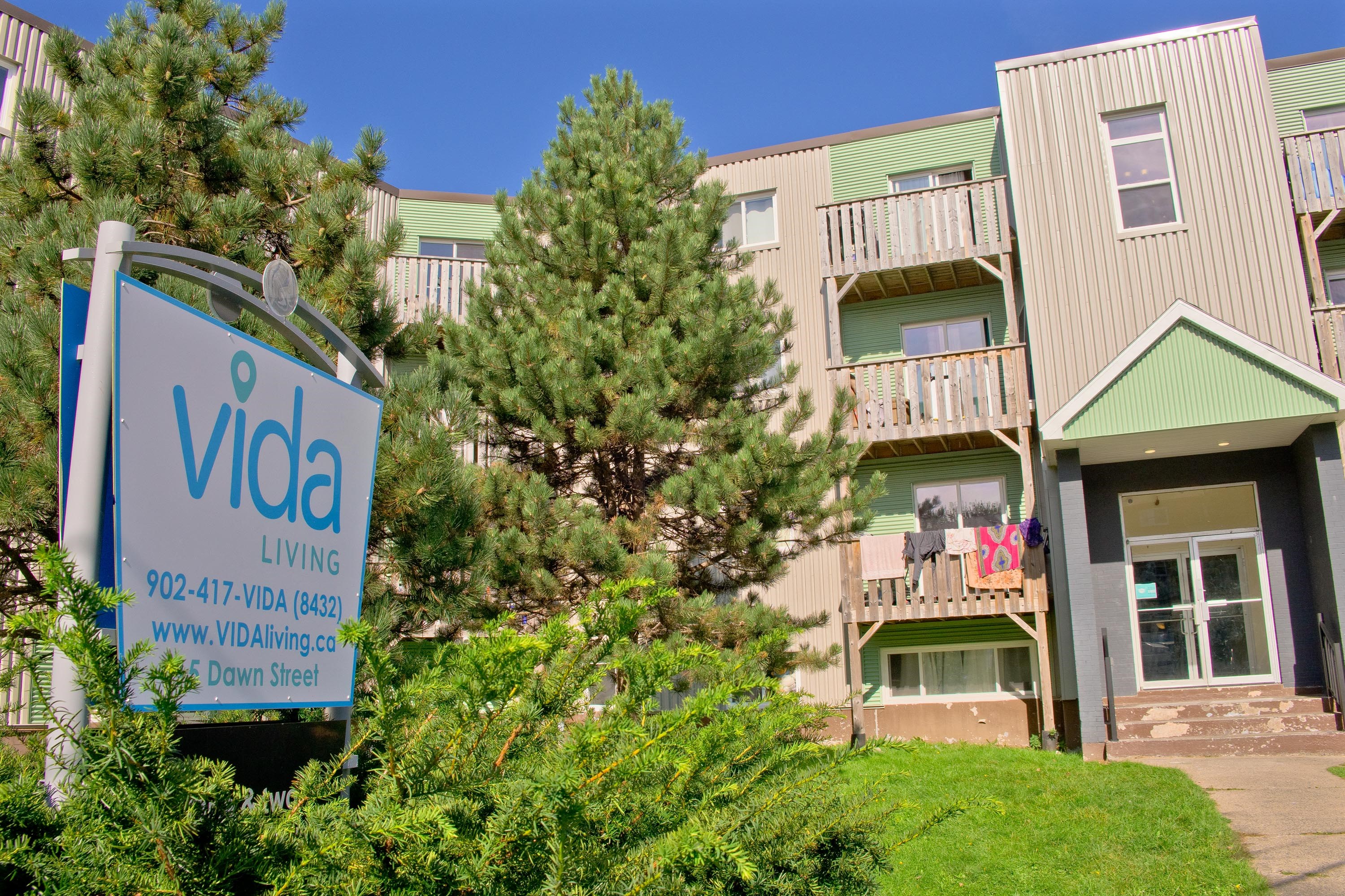 A sign for Vida Living in front of a building.