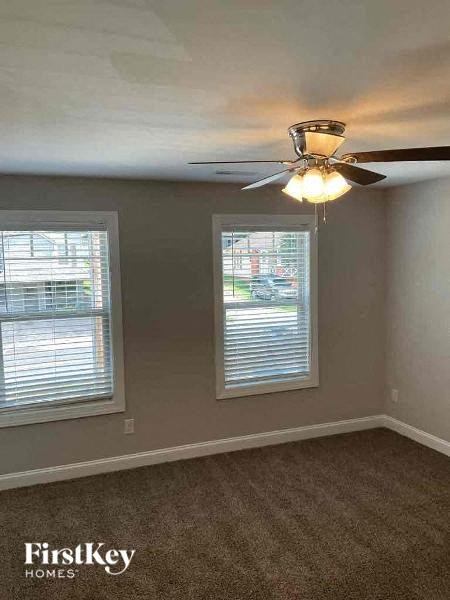 an empty room with a ceiling fan and two windows
